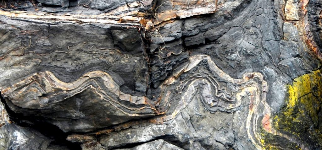 Dark stone with white streaks that looks like it has been bent and folded